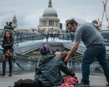 Man giving money to homeless man on footbridge at St. Paul's cathedral 