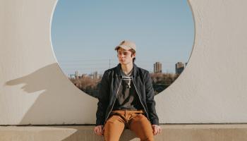 Young man sitting on a ledge of a modernist concrete building