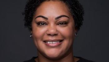 Image of Denise Ramsey's face. She has short black curly hair and is wearing a black long sleeved top.