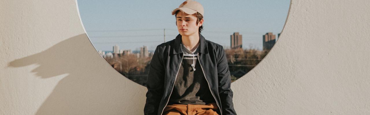 Young man sitting on a ledge of a modernist concrete building