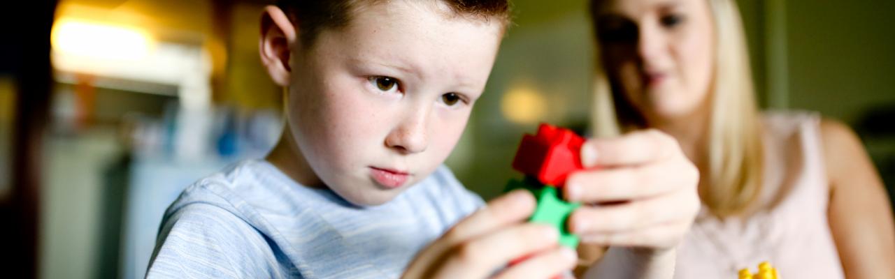 A young boy developing his motor skills with his tutor