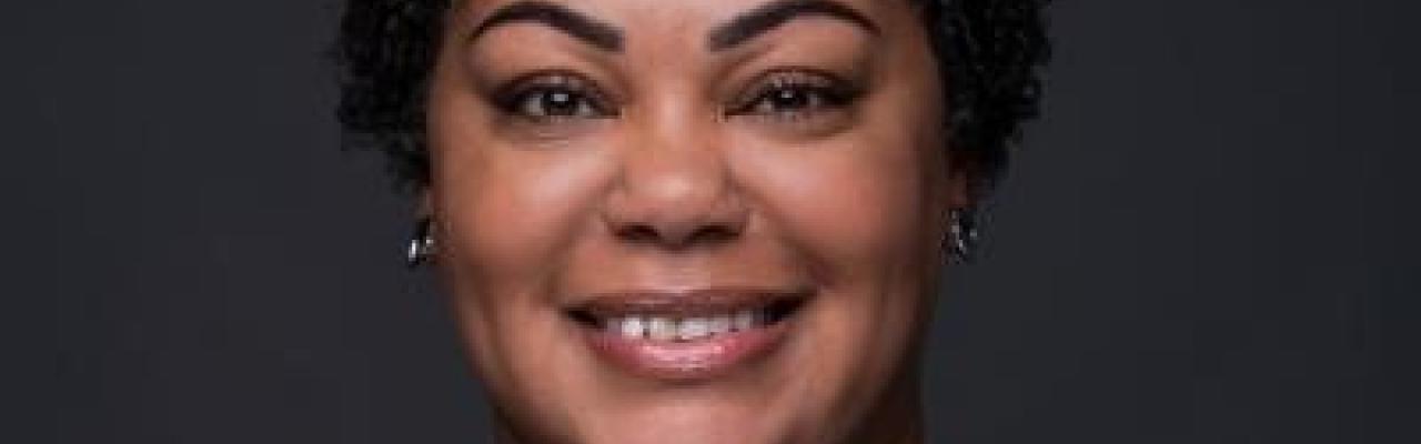 Image of Denise Ramsey's face. She has short black curly hair and is wearing a black long sleeved top.